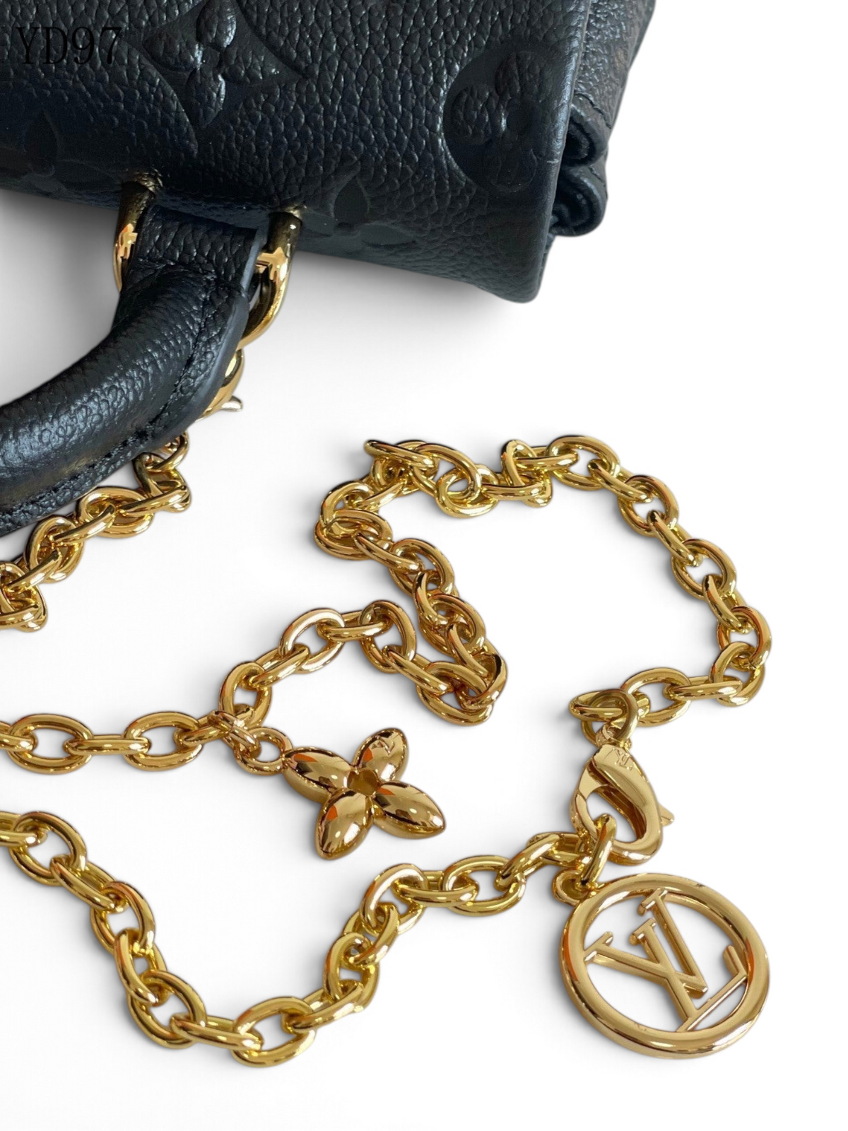 SWORD LUXURY Madeleine Nano çanta, altın tonlu zincir askısı ve LV logolu madalyon detayı ile siyah deri tasarım.