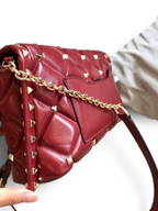 SWORD LUXURY bordo rengi kapitone deri omuz çantası, altın rengi piramit zımba detaylı ve şık zincir askılı tasarım.