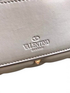SWORD LUXURY gri deri kapitone omuz çantası, üzerinde ikonik piramit çiviler ve Valentino Garavani logosu detaylı.