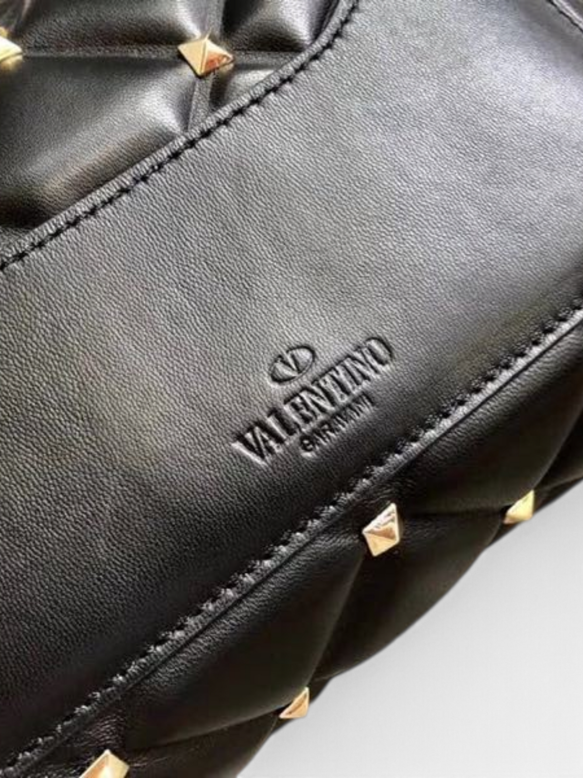 SWORD LUXURY siyah kapitone deri omuz çantası, altın rengi piramit zımba detaylı ve Valentino Garavani logolu.