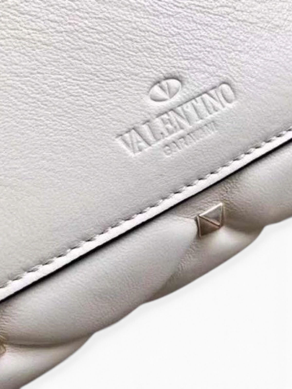 SWORD LUXURY beyaz kapitone deri omuz çantası, ikonik piramit çivili detaylar ve kabartmalı logo ile.