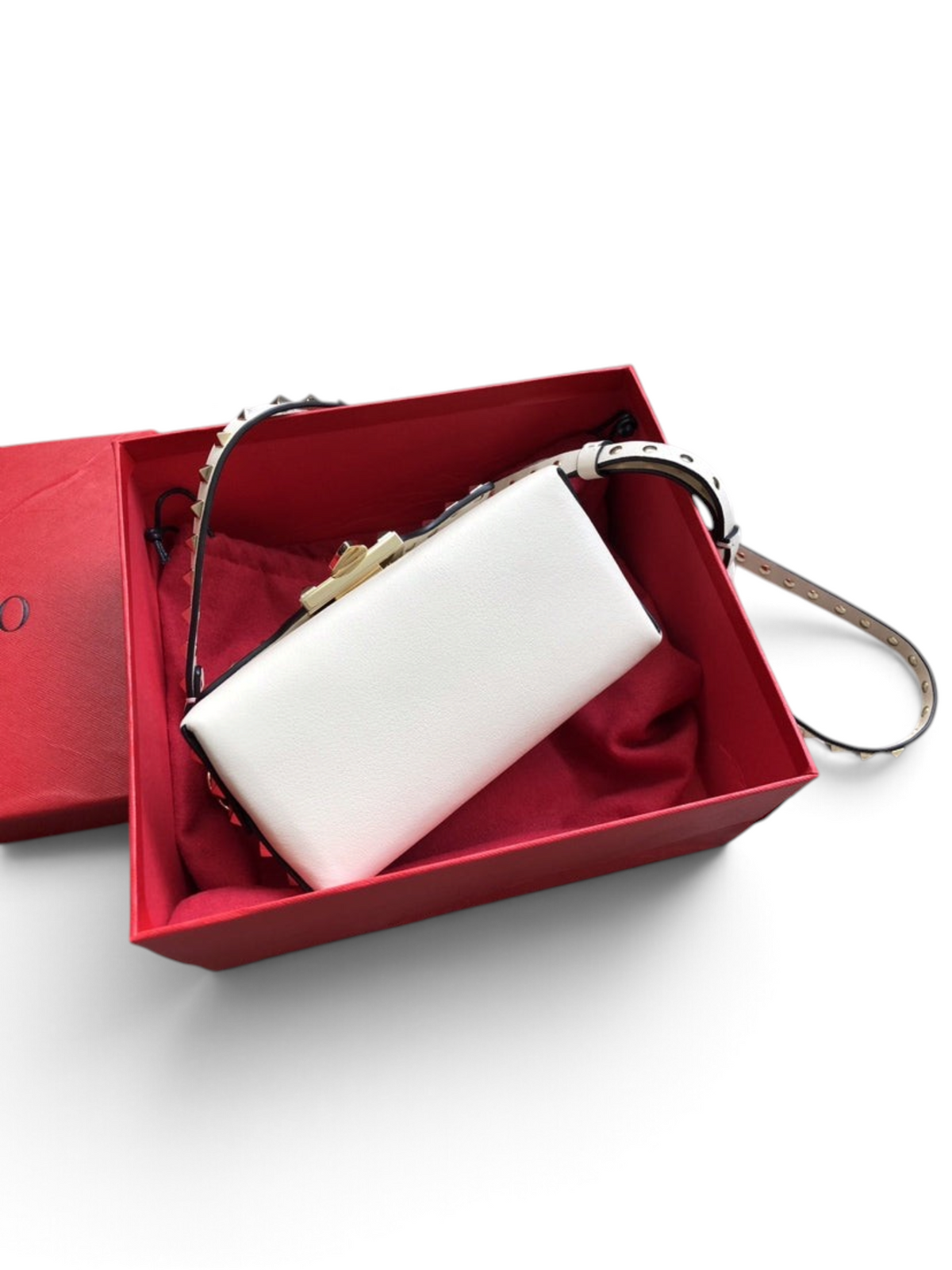 SWORD LUXURY beyaz deri Rockstud omuz çantası, kırmızı kutu içerisinde metal zımba detaylı askısı ile sergileniyor.