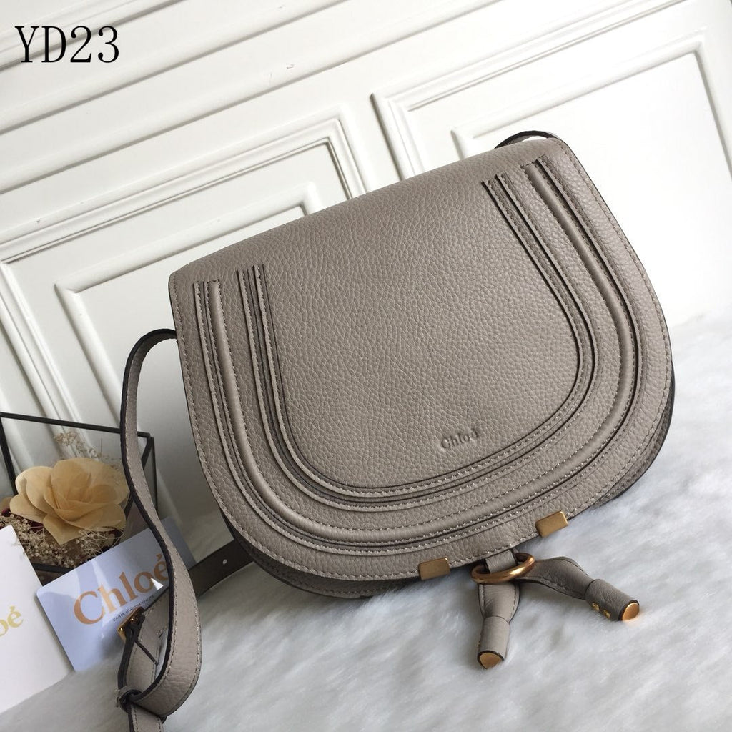 Gray handbag with gold accents on a white surface, featuring the Chloe brand.