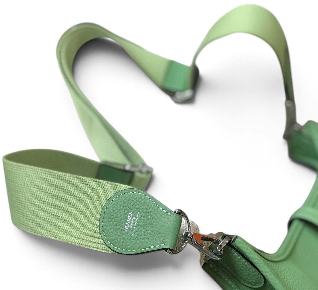 SWORD LUXURY Hermès Evelyne PM 28 çanta, açık yeşil damarlı deri detayları ve ayarlanabilir kanvas askısı ile.