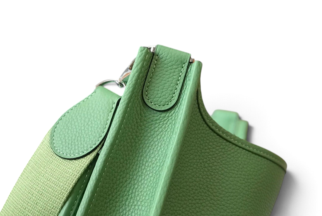 SWORD LUXURY Hermès Evelyne PM 28 çanta, yeşil damarlı deri detayları ve ayarlanabilir kanvas askısı ile yakın çekim.