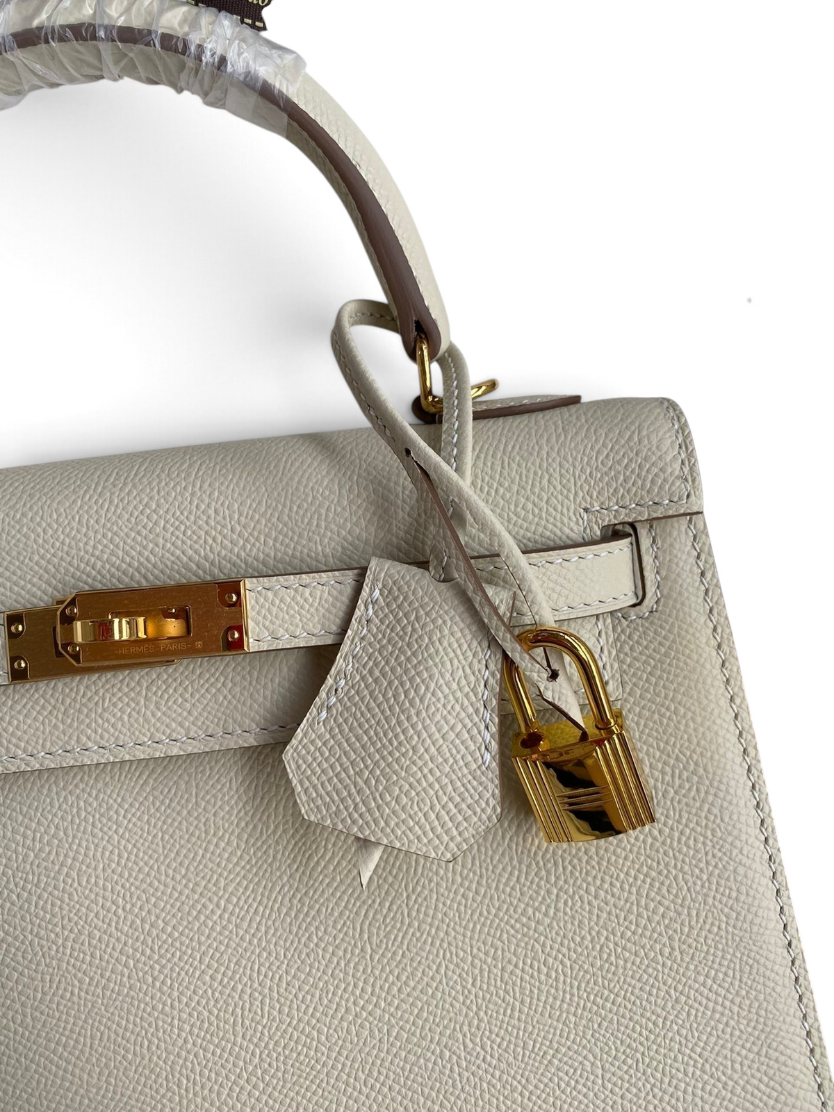 SWORD LUXURY marka, altın tonlu donanıma sahip, bej renkli, dokulu Epsom deri Kelly 25 çanta detayı.