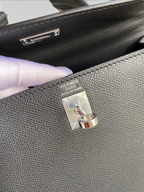 SWORD LUXURY imzalı siyah Epsom deri Hermès Kelly çanta, gümüş paladyum donanım ve ikonik kilit detayı ile.