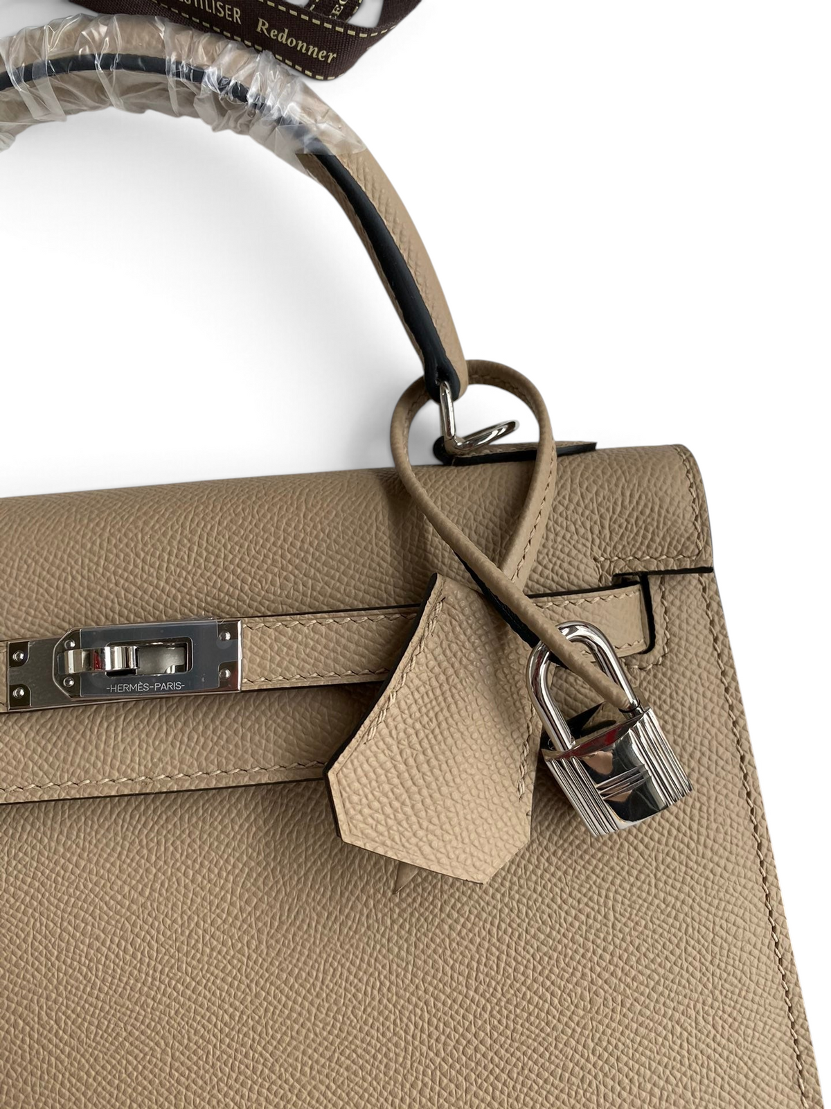 SWORD LUXURY bej renkli, Epsom deri dokulu, gümüş donanımlı ve ikonik kilit detaylı Kelly 25 el çantası.