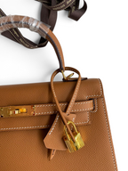 SWORD LUXURY marka taba rengi Epsom deri Kelly 25 çanta, altın tonlu donanım, kilit ve clochette detaylı.