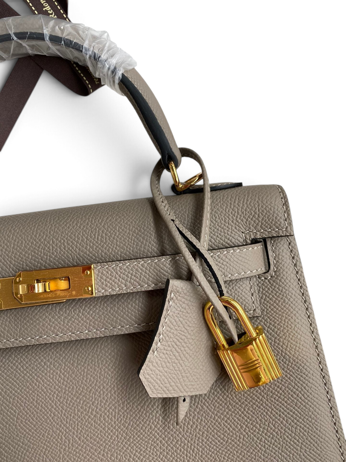 SWORD LUXURY gri Epsom deri Kelly 25 çanta, altın tonlu donanım, kilit ve anahtarlı clochette detaylı.