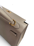 SWORD LUXURY marka gri Epsom deri Kelly 25 çanta, altın tonlu donanım ve zarif el işçiliği detayları ile.