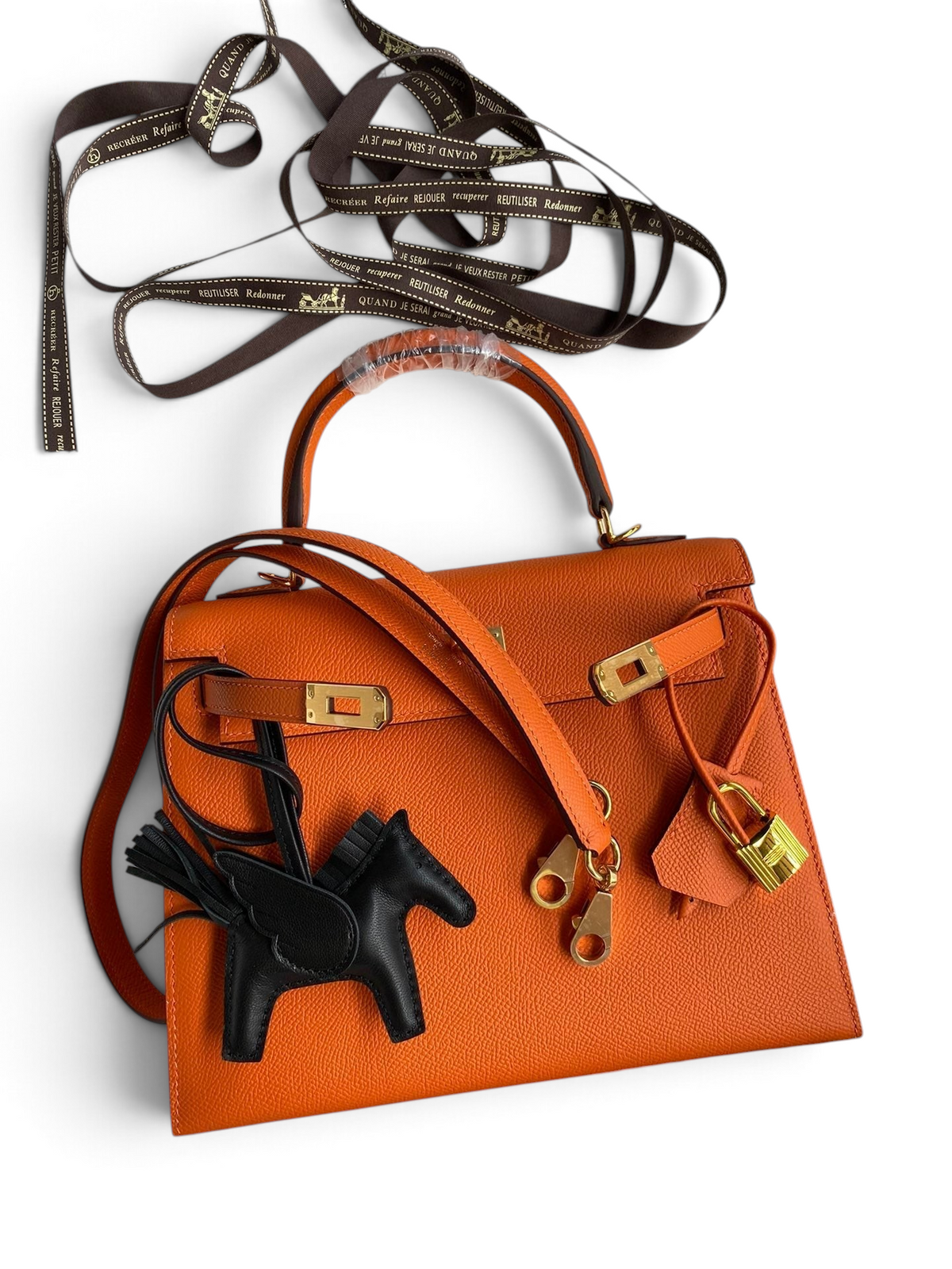 SWORD LUXURY imzalı, turuncu Epsom deri Hermès Kelly 25 çanta, altın tonlu donanım ve siyah at figürlü aksesuar ile.
