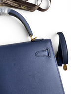 SWORD LUXURY lacivert Epsom deri Kelly 25 çanta, altın tonlu donanım ve çıkarılabilir omuz askısı ile detaylandırılmıştır.