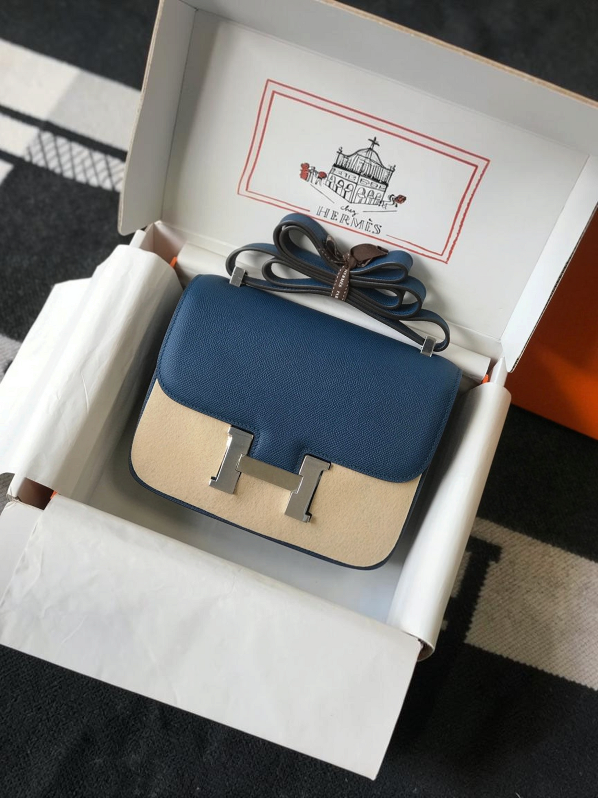 SWORD LUXURY marka, mavi ve bej renkli, paladyum H tokalı, deri Hermès Constance 18 çanta, orijinal kutusunda.