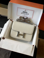 SWORD LUXURY marka krem rengi deri Hermès Constance 18 çanta, gümüş tonlu H tokası ile kutusunda sergileniyor.
