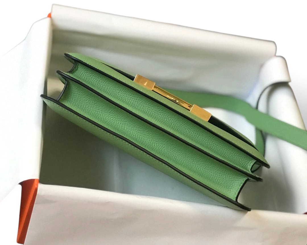 SWORD LUXURY marka yeşil Epsom deri Hermès Constance 18 çanta, altın tonlu H tokası ve zarif yan profili ile.