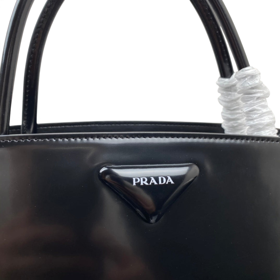 SWORD LUXURY Prada Supernova siyah fırçalanmış deri çanta, ikonik üçgen logo plakalı ve şık üst saplı tasarım.