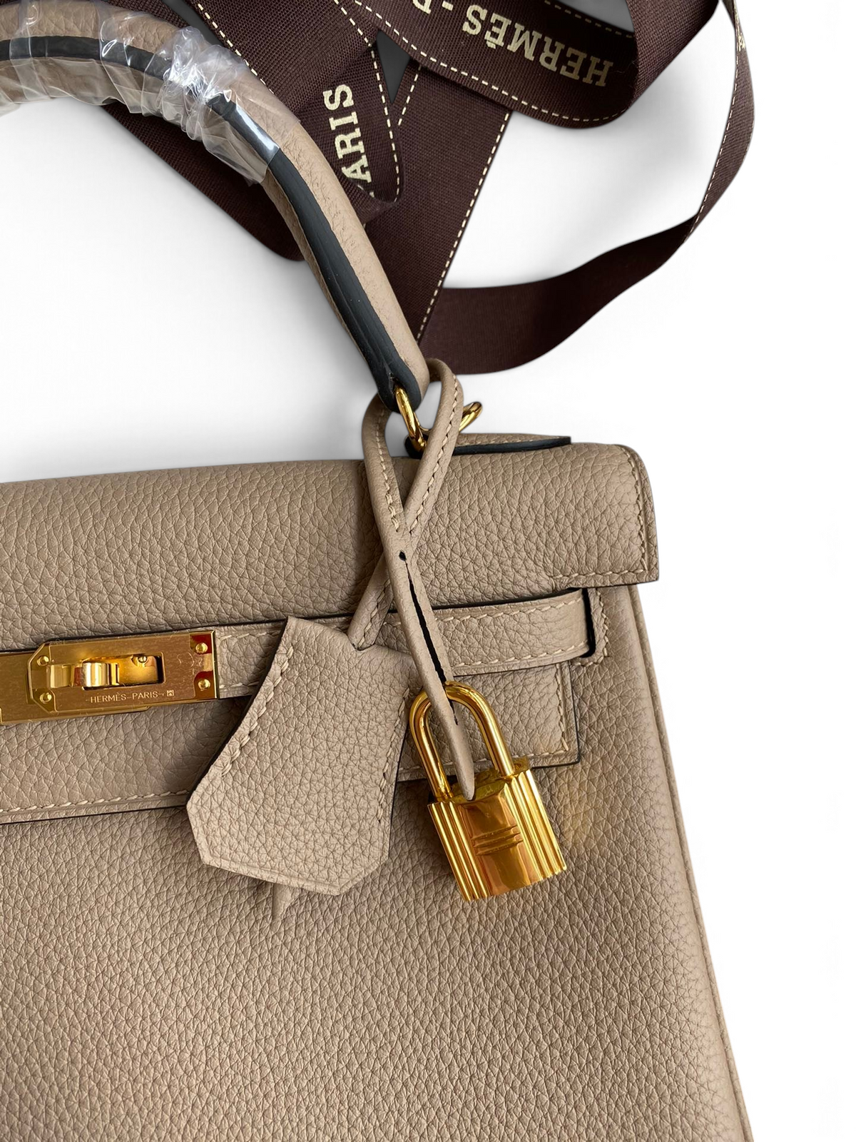 SWORD LUXURY imzalı, altın donanımlı ve kilit detaylı, bej renkli Togo deri Kelly 25 el çantası.