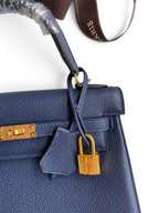 SWORD LUXURY lacivert Togo deri Kelly 25 çanta, altın rengi kilit ve ikonik turn-lock kapama detaylı.