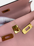 SWORD LUXURY Kelly 25 pembe Togo deri çanta, altın rengi metal kilit detayları ve iç kısımdaki kabartma logo.