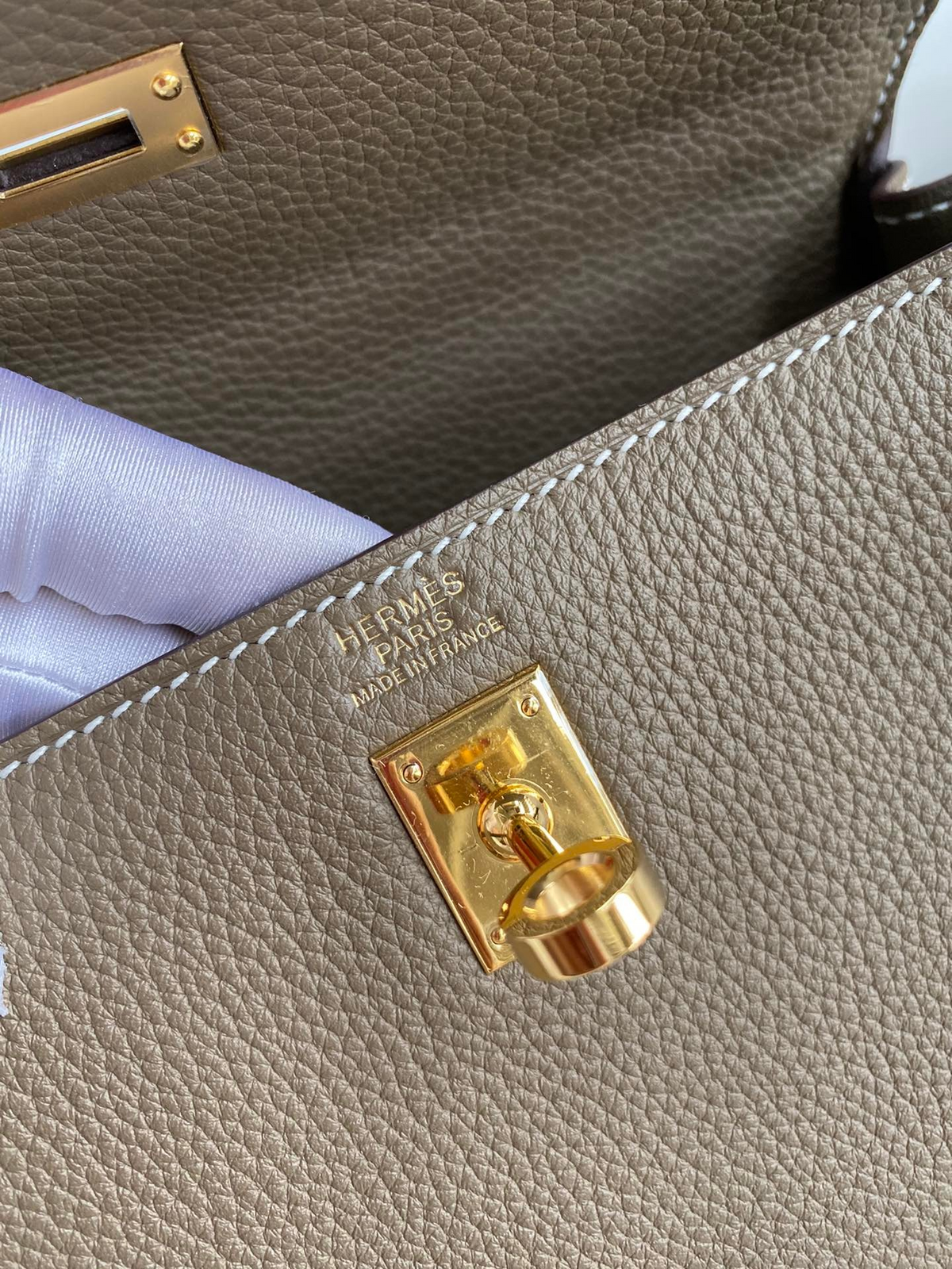 SWORD LUXURY Kelly 25 Togo deri çanta, altın rengi metal kilit detayı ve iç kısımdaki Hermès damgası ile yakın çekim.