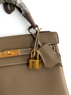SWORD LUXURY Kelly 25 Togo deri çanta, altın donanımlı, ikonik kilit ve el dikişi detaylı, taupe renkli lüks tasarım.