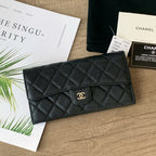 Black quilted Chanel wallet on a wooden surface with branded paper and card.