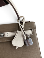 SWORD LUXURY marka, gri ve beyaz renkli, Epsom deri Hermès Kelly 25 çanta, gümüş kilit ve detaylı tasarım.