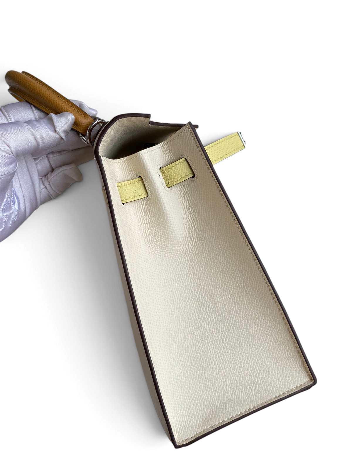 SWORD LUXURY Hermès Kelly 25 Epsom deri çanta, beyaz gövde, sarı detaylar ve kahverengi saplı yan görünüm.