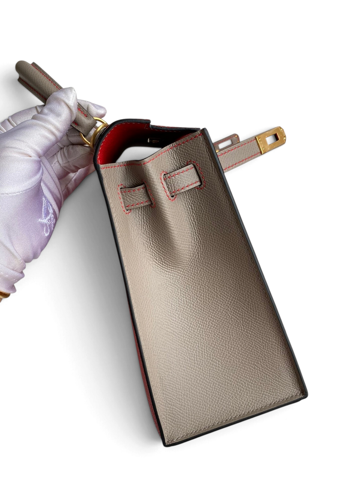 SWORD LUXURY marka, gri Epsom deri Hermès Kelly 25 çanta, kırmızı dikiş detaylı ve altın rengi metal kilitli yan görünüm