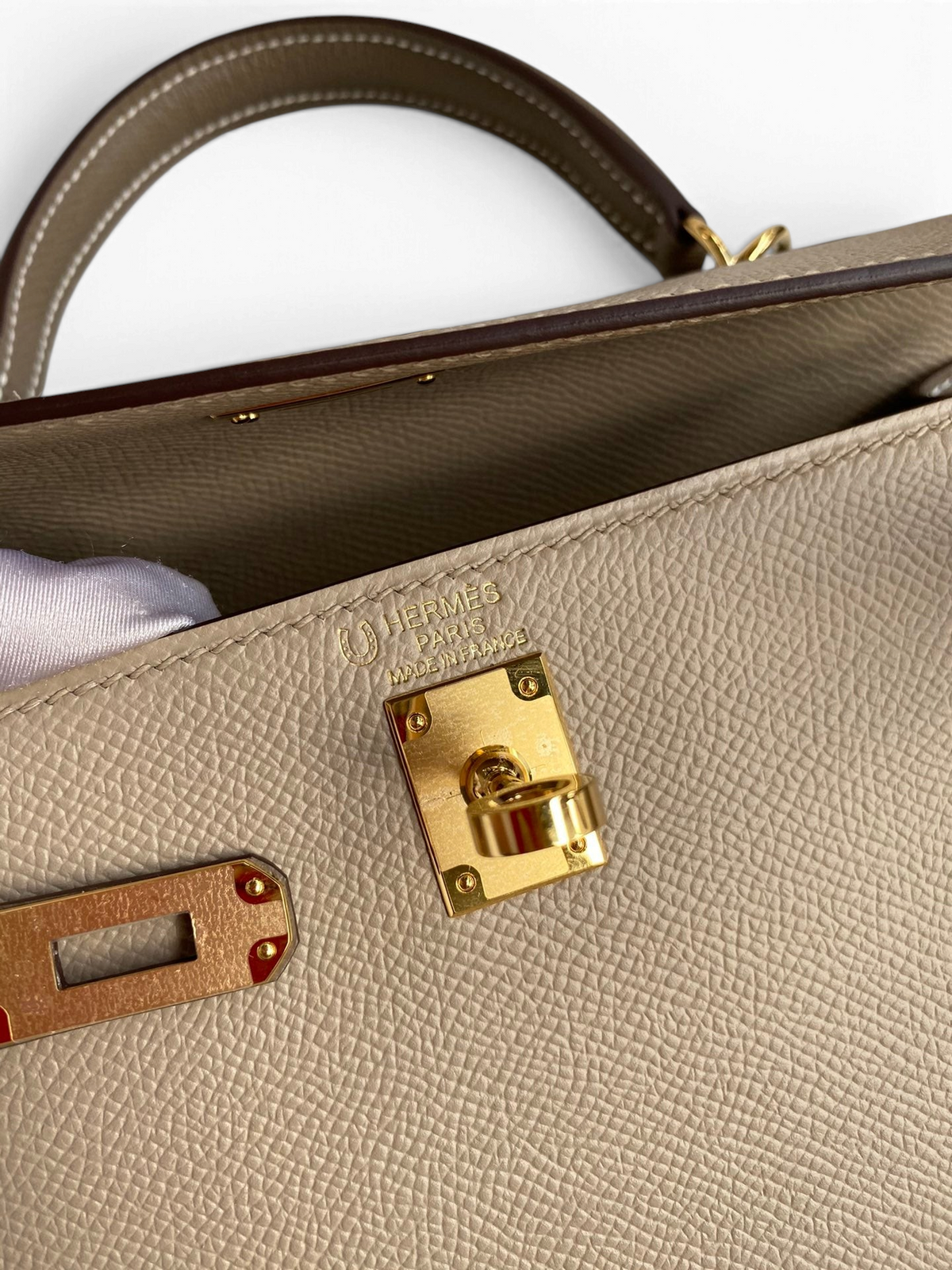 SWORD LUXURY Hermès Kelly 25 çanta, altın donanımlı bej Epsom deri detayları ve ikonik kilit mekanizması.