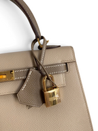 SWORD LUXURY marka, altın donanımlı ve asma kilit detaylı, bej renkli Epsom deri Hermès Kelly 25 çanta.