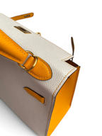 SWORD LUXURY Hermès Kelly 25 çanta, beyaz ve sarı Epsom deri detaylı, zarif dikişli ve altın tonlu metal aksesuarlı.