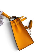 SWORD LUXURY marka, sarı Epsom deri Hermès Kelly 25 çanta, yan profilden görünüm ve detaylı doku.