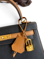 SWORD LUXURY imzalı siyah Epsom deri Hermès Kelly 25 çanta, altın donanım ve taba rengi detaylarla.