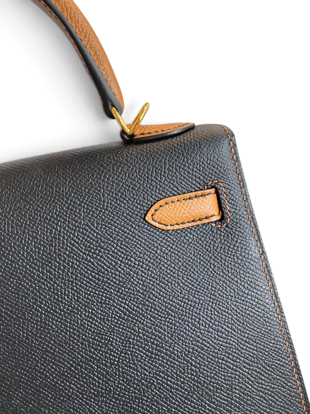 SWORD LUXURY siyah Epsom deri Kelly 25 çanta, altın donanım ve taba rengi detaylı sap ile zarif bir görünüm sunuyor.