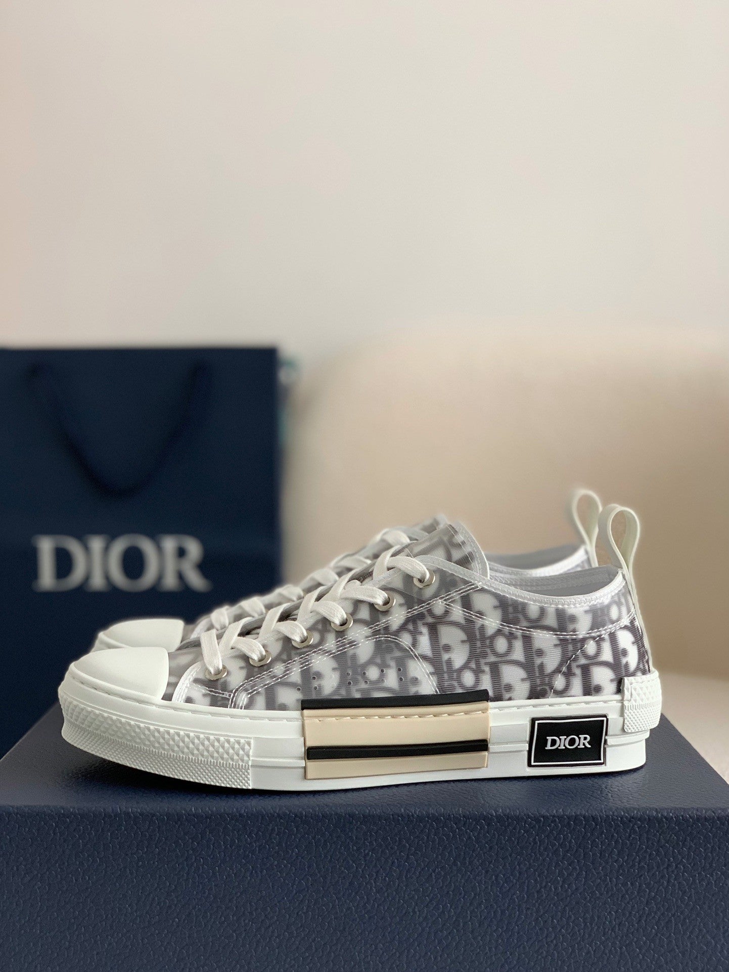 Dior sneaker with logo pattern on a dark surface