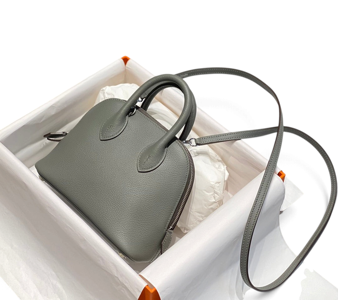SWORD LUXURY gri deri Hermès Bolide Mini 19 çanta, kutu içerisinde, yuvarlak silüetli ve omuz askılı.