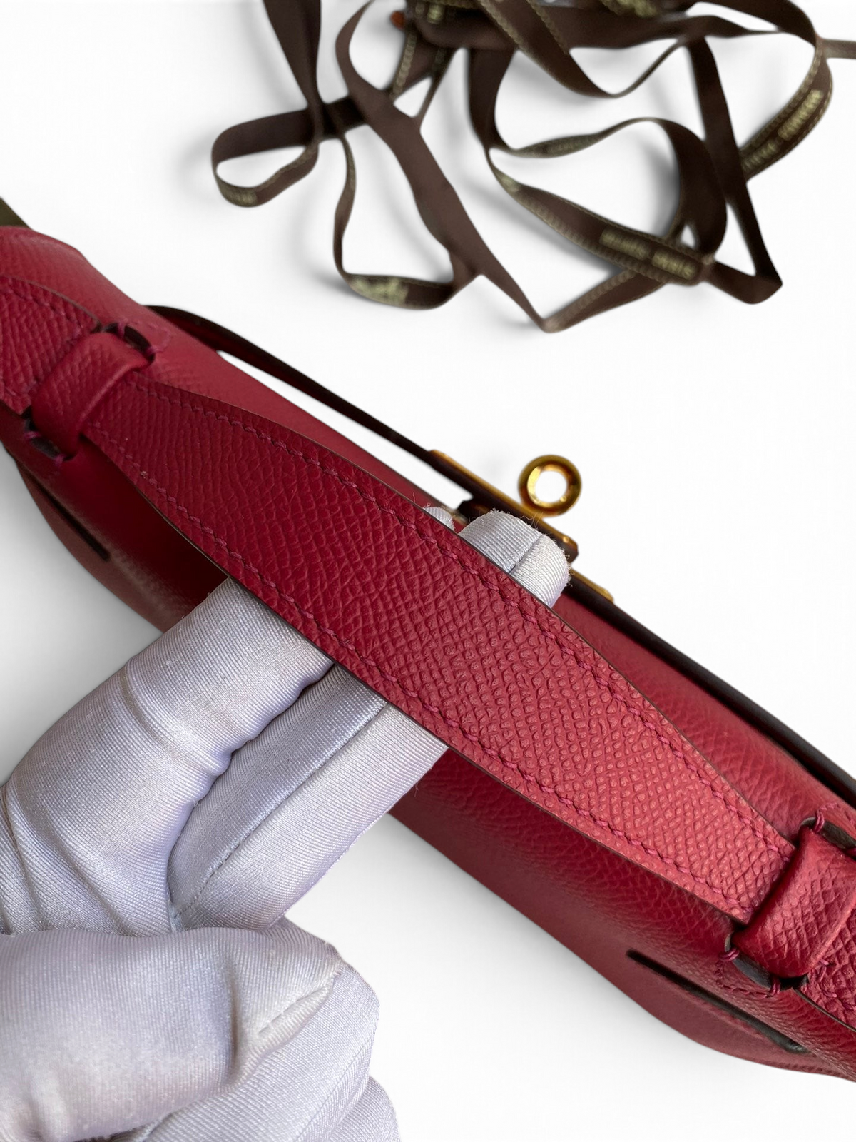 SWORD LUXURY marka, 22 cm boyutunda, kırmızı Epsom deri Mini Kelly çanta, üstten tutmalı ve altın detaylı kilitli.