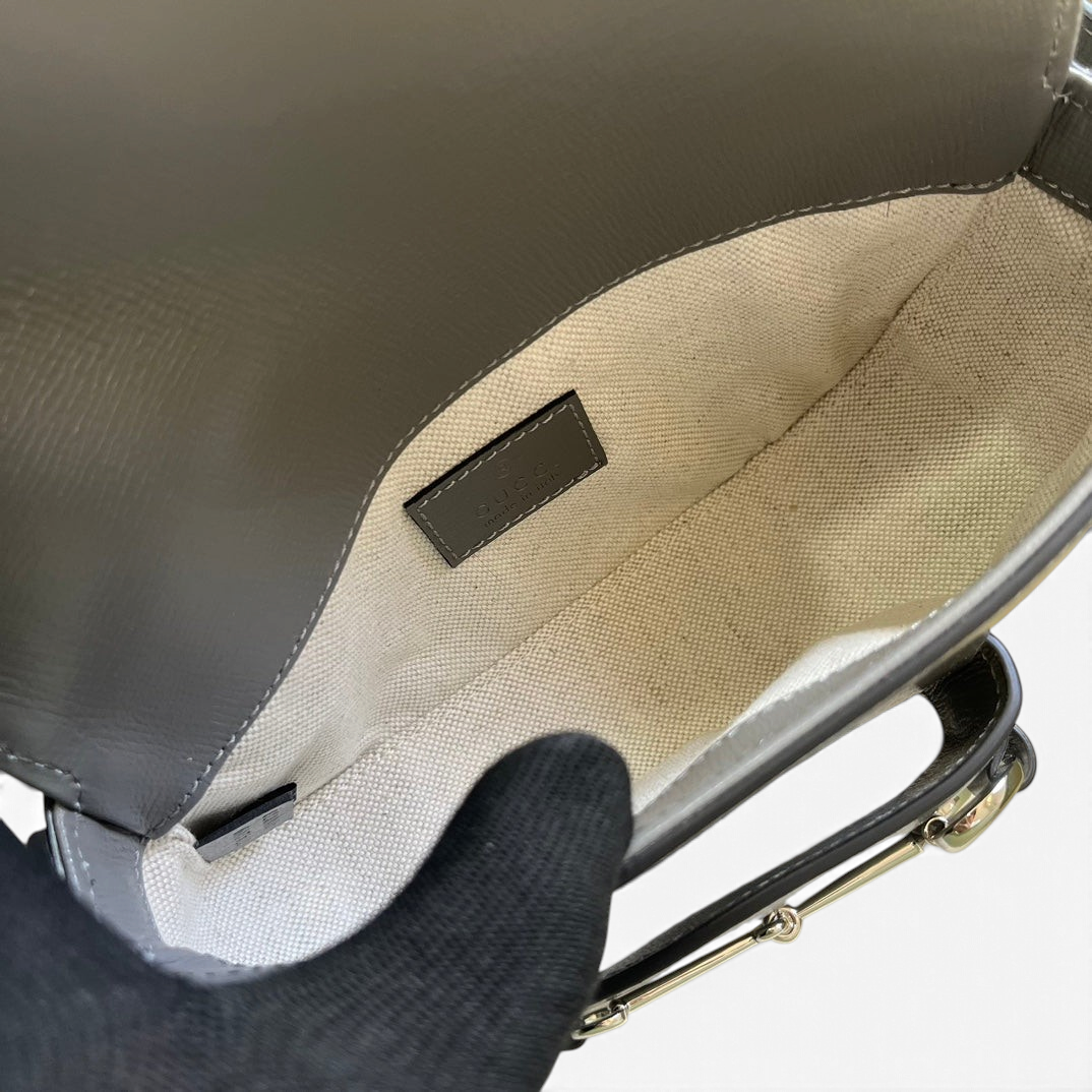 SWORD LUXURY Horsebit 1955 mini çanta içi, bej astarlı ve deri etiketli, üstten görünüm.