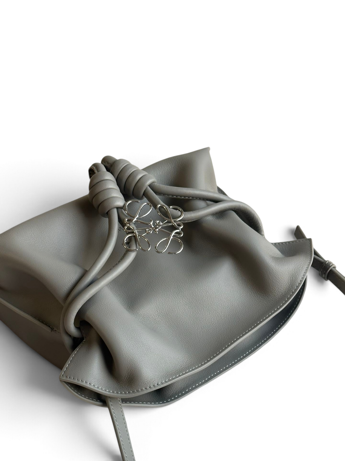 SWORD LUXURY gri yumuşak dana derisi Flamenco büzgülü çanta, ikonik düğümlü yan detaylara ve gümüş metal logoya sahip.