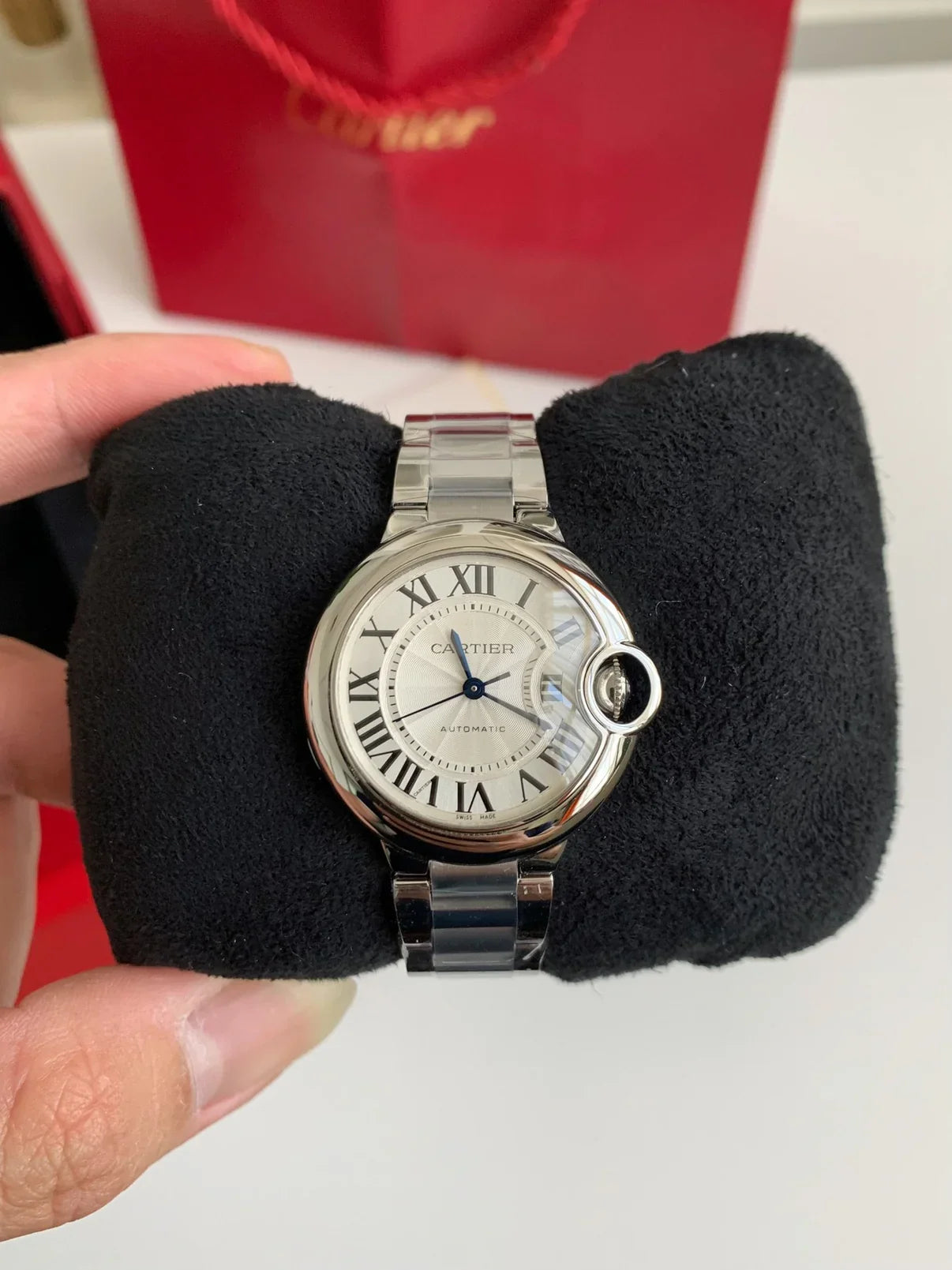 Cartier watch on a black cushion with a red box in the background