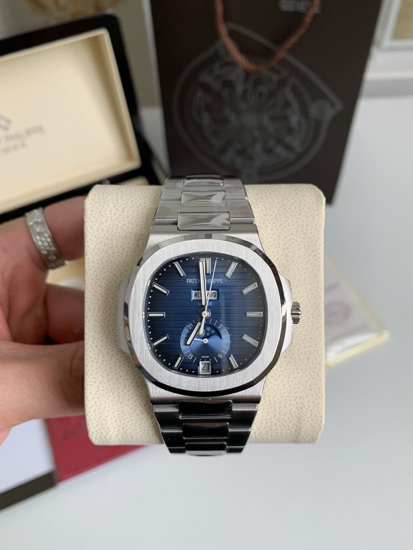 Silver watch with blue face on a display stand, with a blurred background