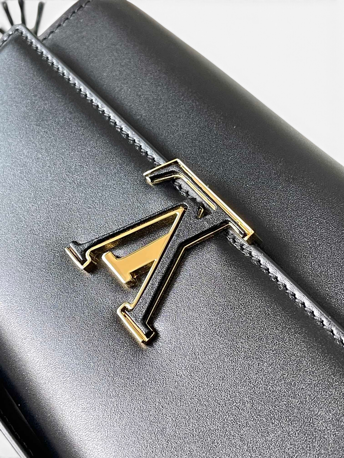 SWORD LUXURY siyah deri Capucines cüzdan üzerinde altın rengi LV baş harfleri detayı