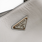 SWORD LUXURY Prada tote çanta üzerinde altın tonlu metal üçgen logo detaylı yumuşak dokulu beyaz deri yüzey