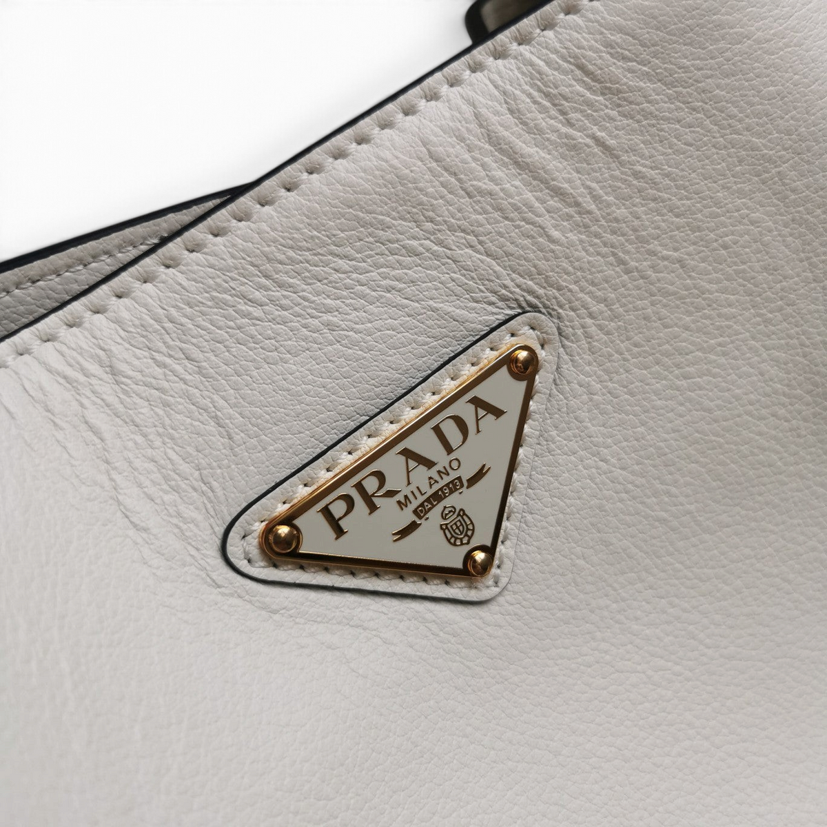 SWORD LUXURY Prada tote çanta üzerinde altın tonlu metal üçgen logo detaylı yumuşak dokulu beyaz deri yüzey