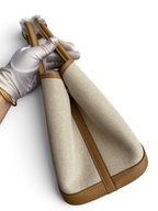 SWORD LUXURY Hermès Garden Party 30 çanta, bej kanvas ve taba rengi deri detaylı, kutu içerisinde tutulurken.