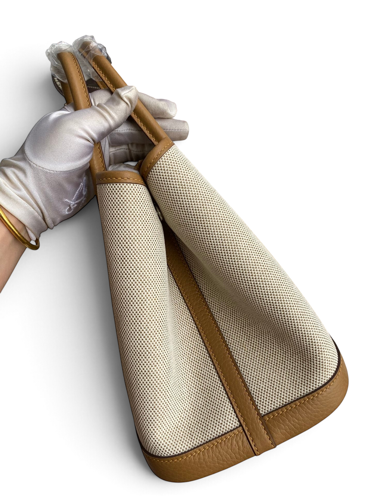 SWORD LUXURY Hermès Garden Party 30 çanta, bej kanvas ve taba rengi deri detaylı, kutu içerisinde tutulurken.