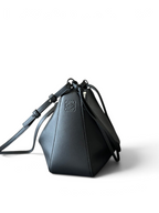 SWORD LUXURY siyah deri Loewe Mini Hammock çanta, yan panelleri ve gümüş detaylarıyla şık bir tasarım sunuyor.