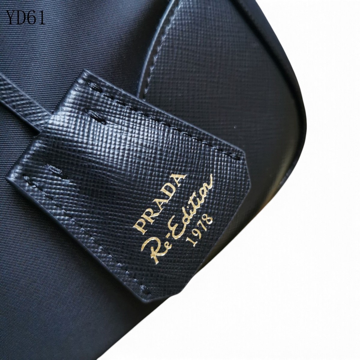 SWORD LUXURY Prada Re-Edition 1978 siyah Re-Nylon ve Saffiano deri çanta detayı, altın rengi logo baskılı deri etiket.